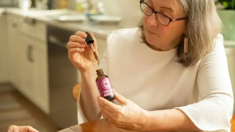 Older woman holding a full spectrum 3,000mg CBD oil tincture and dropper